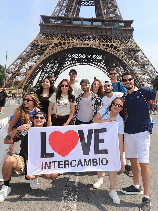 Grupo da Love Intercâmbio com bandeira em frente à Torre Eiffel
